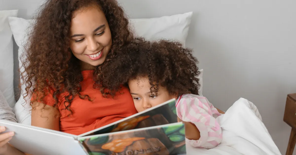 Mother reading with her daughter at home
