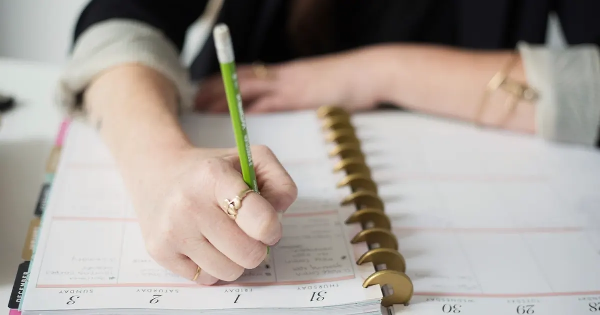 Student writing a revision timetable in a spiral planner
