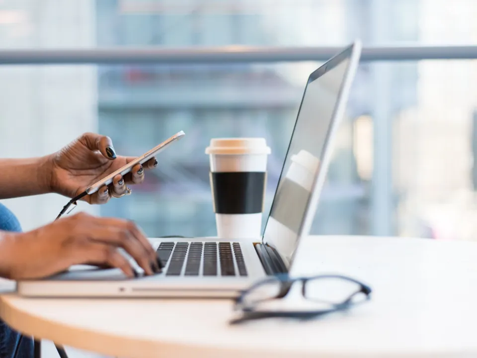 Parent messaging on a phone next to a laptop to book a trial class